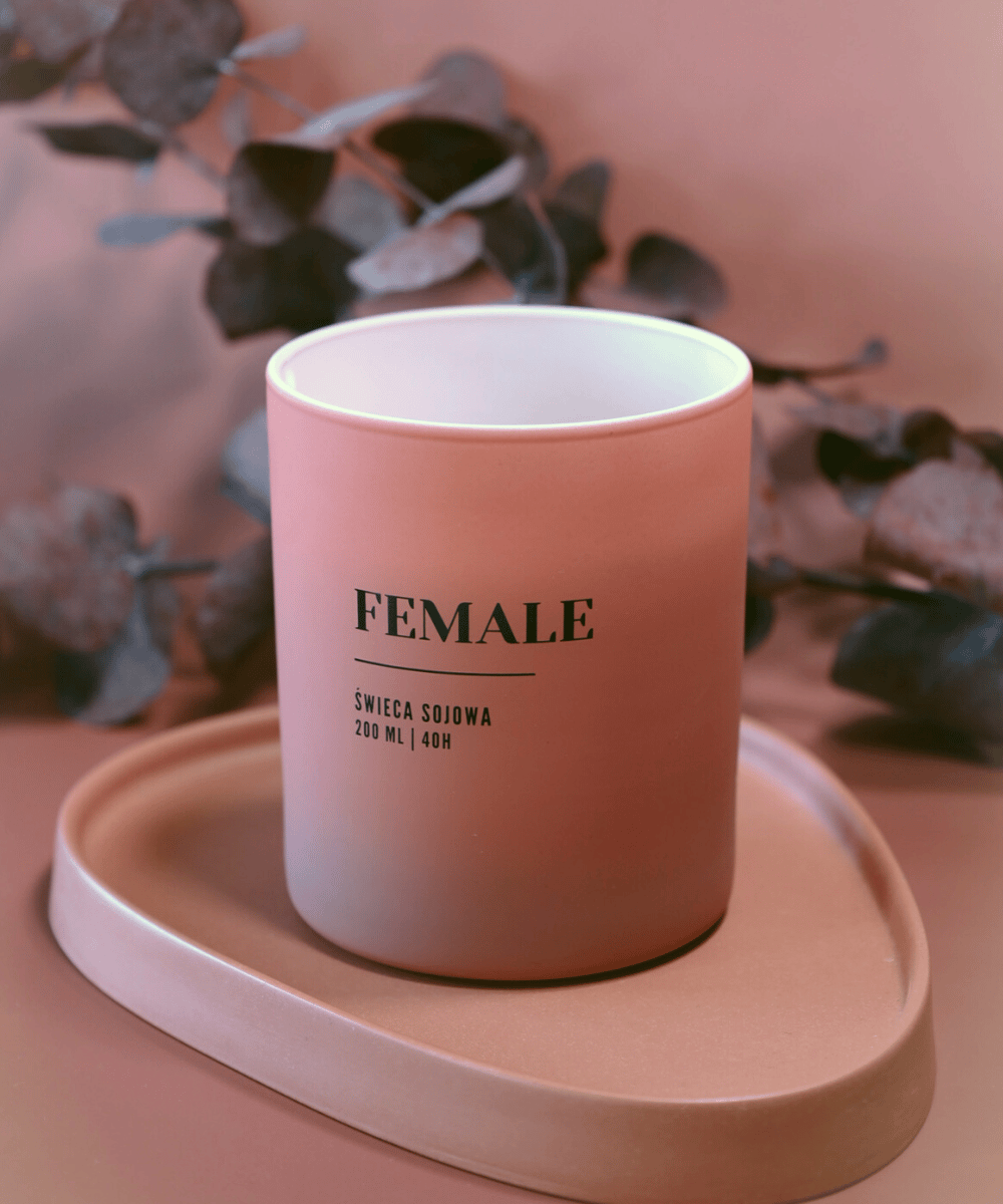 Na zdjęciu widać świecę o zapachu ,,female'' w kobiecym, różowym opakowniu.