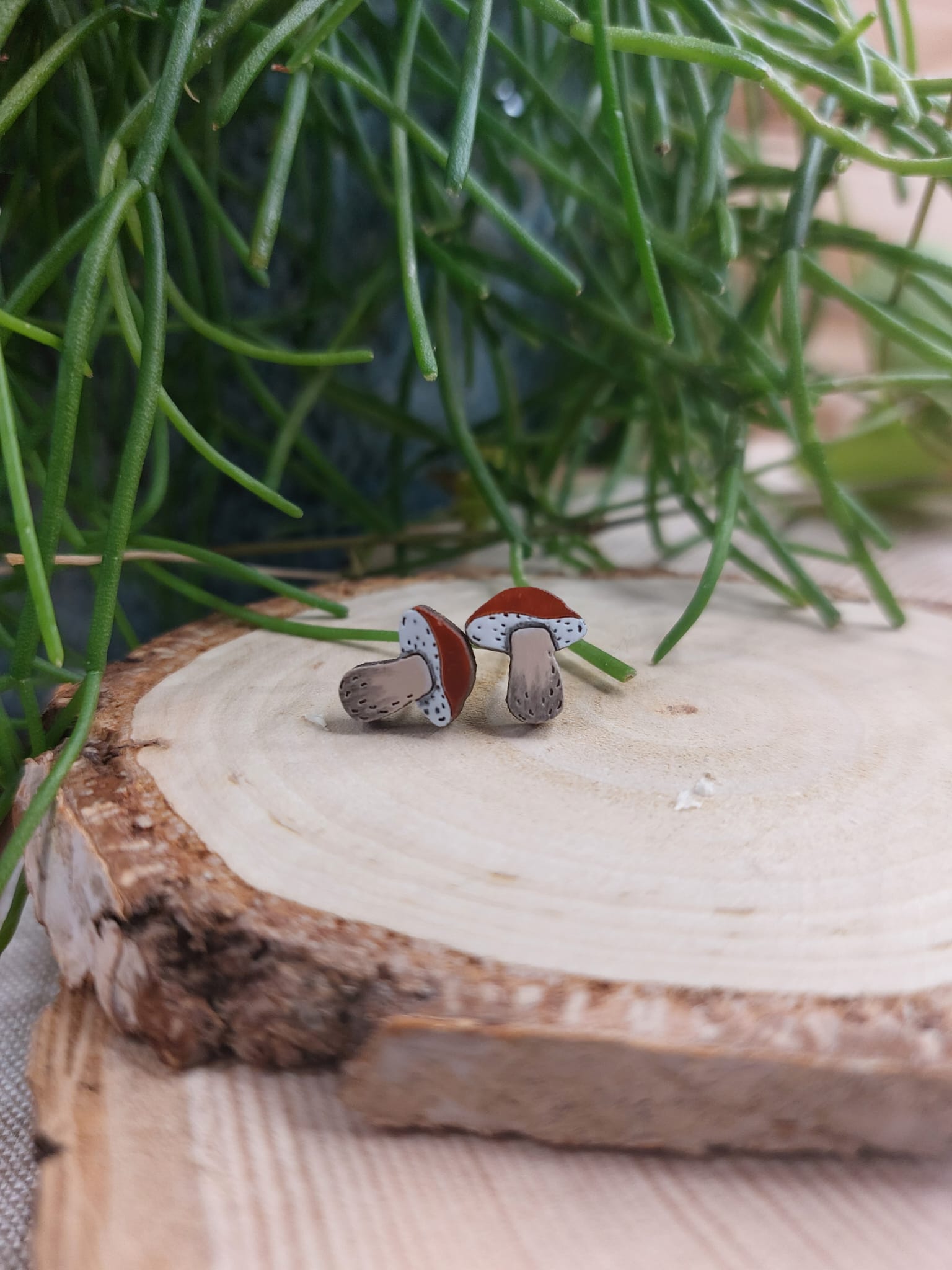 Na zdjęciu widać ręcznie malowane, drewniane kolczyki z motywem grzybka.